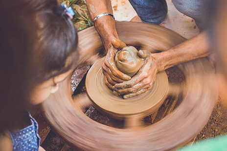 Hands working at a pottery wheel